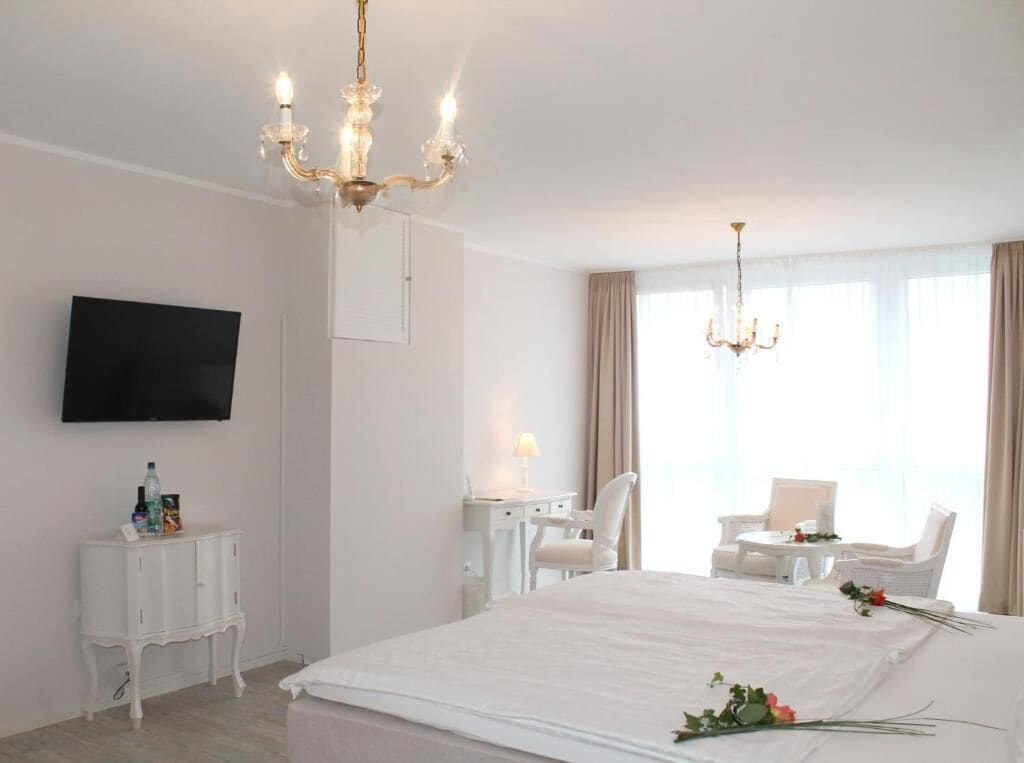 Une chambre d’hôtel avec un grand lit, un téléviseur fixé au mur, un bureau avec une lampe et une chaise.