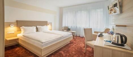 Una habitación de hotel con una cama grande, un escritorio, una silla y una mesita.