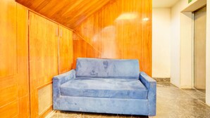 A blue sofa in a room with wooden walls and a tiled floor. - Super Collection O Airport Road Hotel (Ahmedabad)