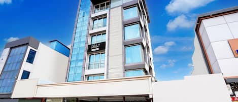 A modern multi-story building with a glass facade, a visible sign for 'Collection', and a covered entrance area.