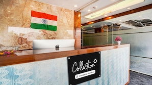 A reception desk with a marble wall, an Indian flag, and a sign reading "Collection Company-Serviced". - Super Collection O Airport Road Hotel (Ahmedabad)