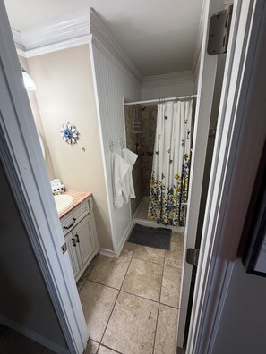 Un baño con ducha, lavabo y un perchero para toallas.