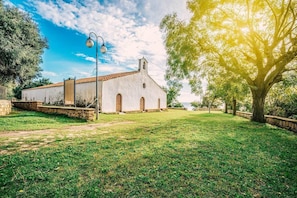 A white building with a tiled roof, surrounded by a grassy area and trees. - Large cozy house 400 meters from the sea ideal for families and groups (Santa Maria Navarrese)