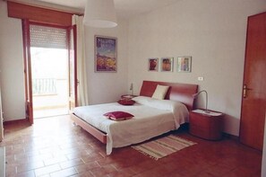 A bedroom with a bed, bedside table, and a poster on the wall. - Large cozy house 400 meters from the sea ideal for families and groups (Santa Maria Navarrese)