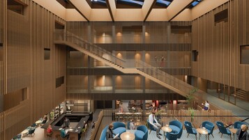 Eine geräumige Lobby mit einer zentralen Treppe, Sitzgelegenheiten und einer Bar.