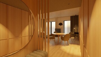 Ein modernes Interieur mit einer Holztreppe, einem Essbereich mit rundem Tisch und Stühlen sowie Außenblick durch große Fenster.