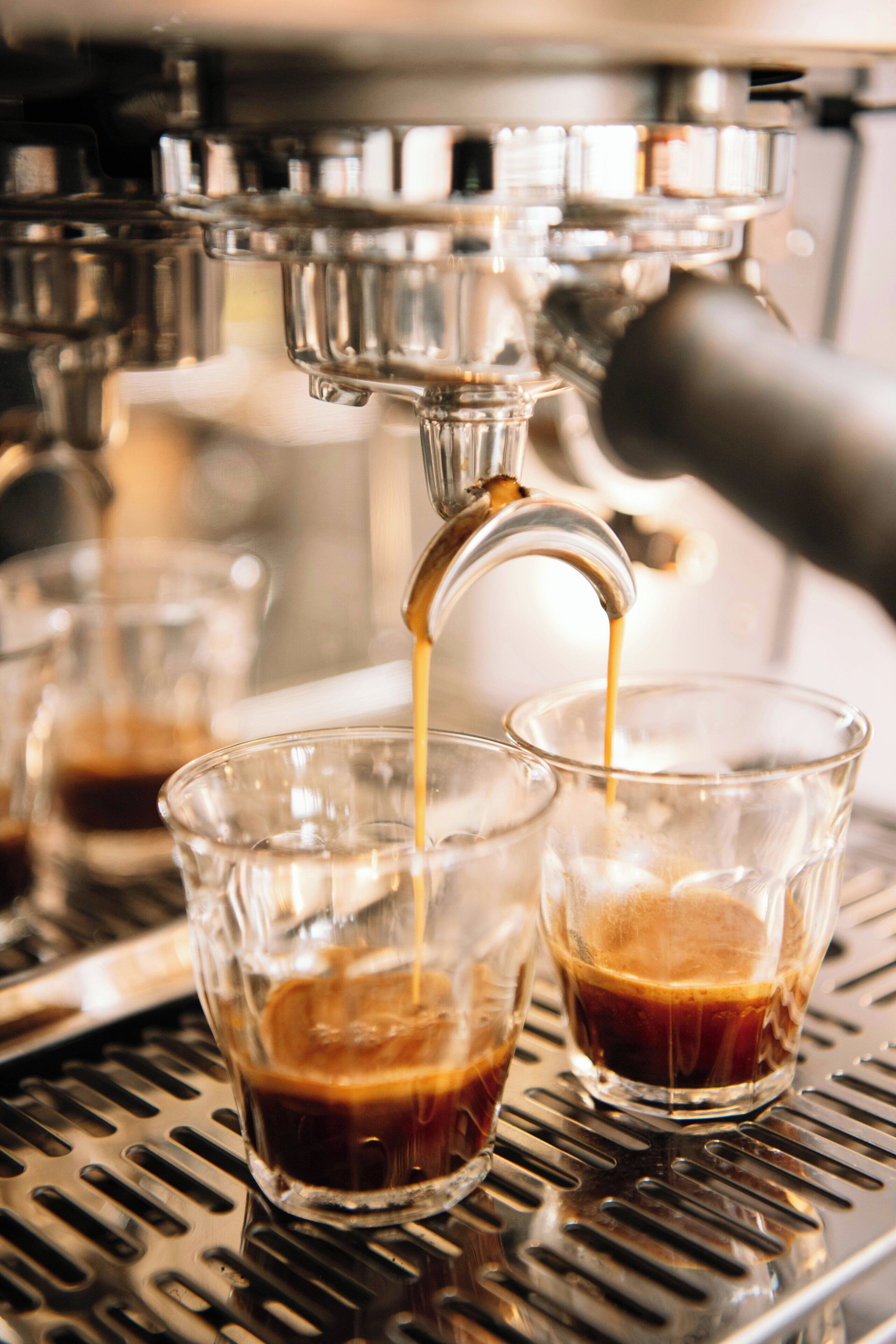 Een koffieapparaat schenkt koffie in twee glazen.
