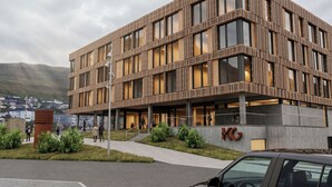 A modern building with a wooden facade, large windows, and a visible entrance. - KG Hotel (Klaksvik)
