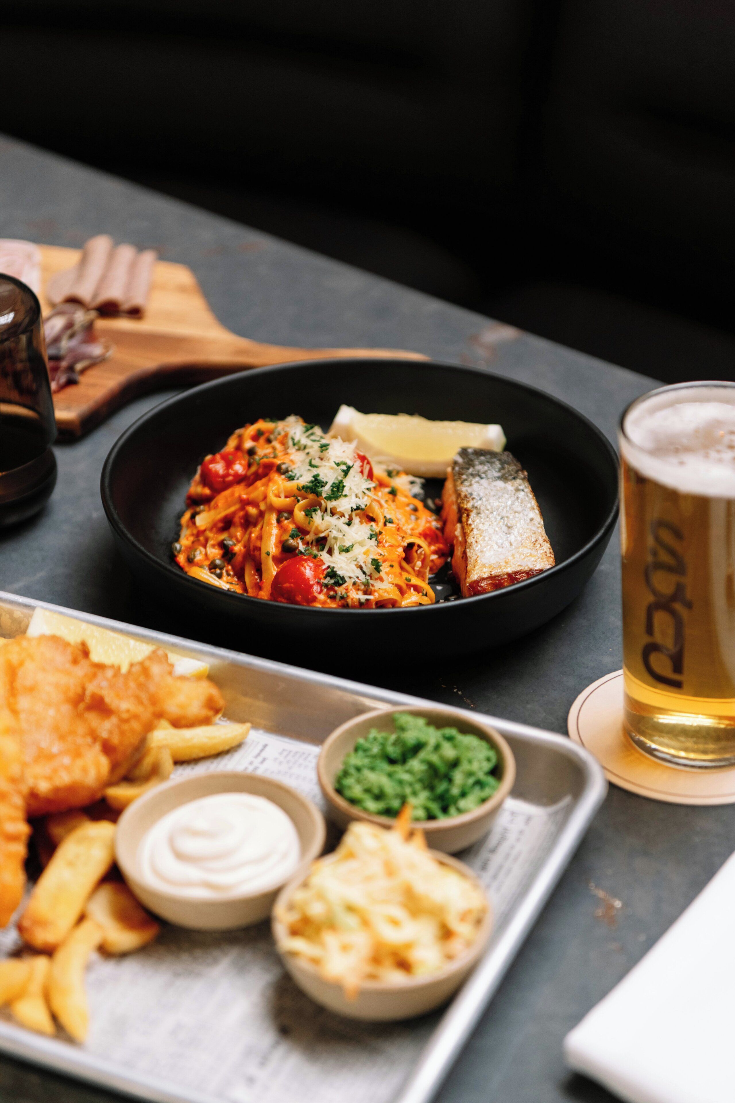 A meal with pasta, fish, and a drink on a table.