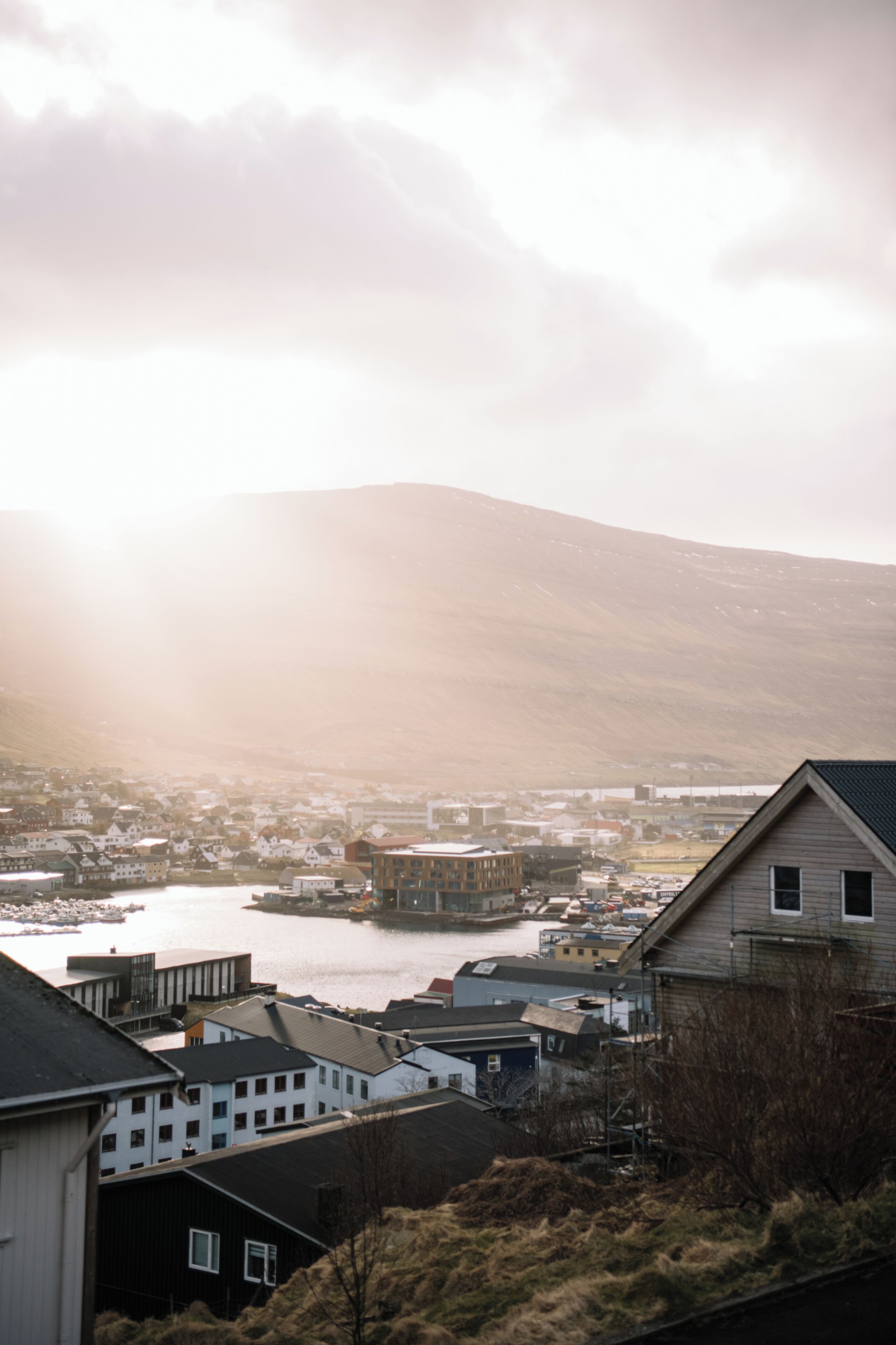 A coastal town with buildings near a body of water and a mountain in the background.