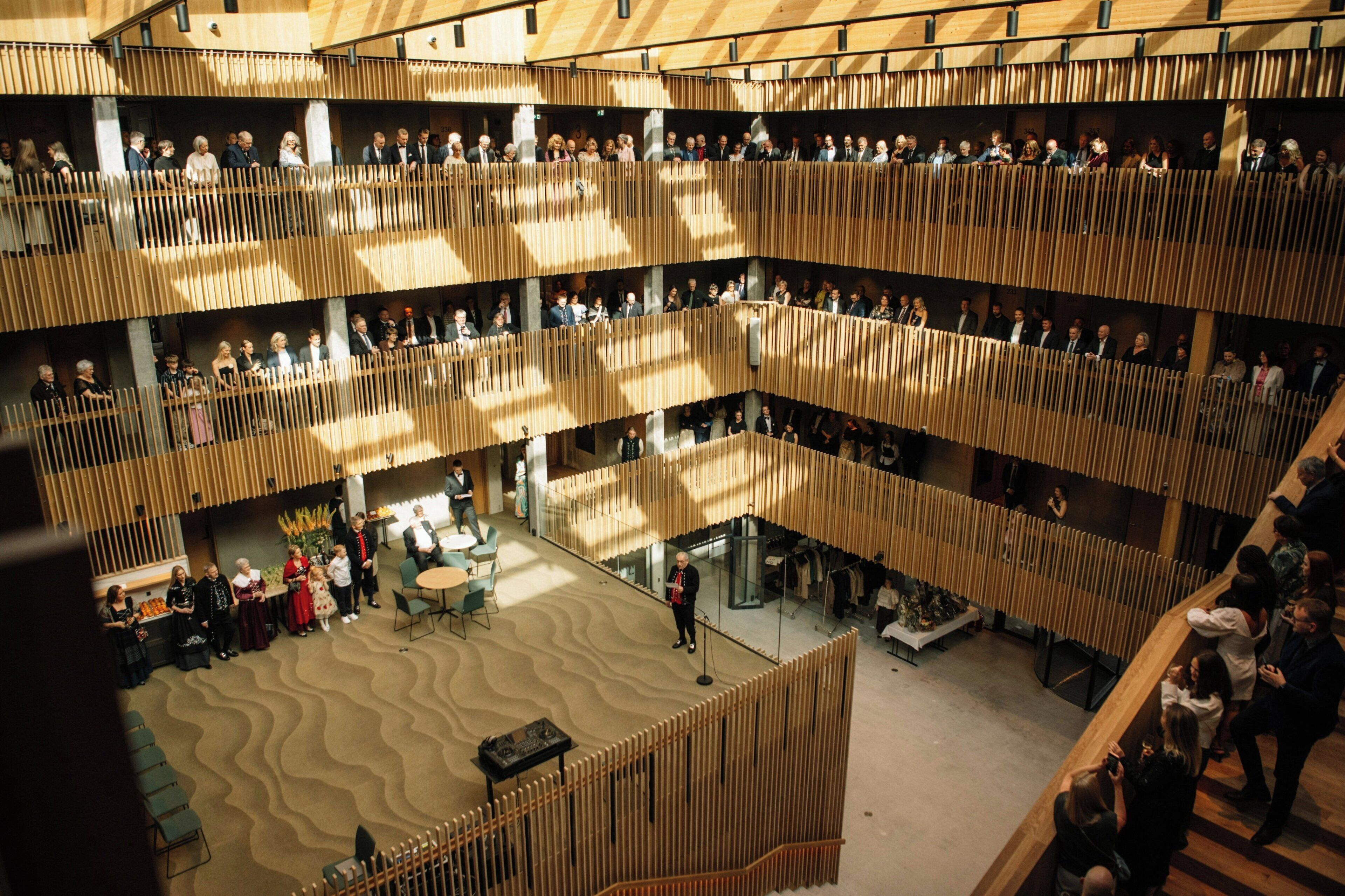 A multi-level atrium with a modern design, featuring a central open space with seating and a lower level with a staircase.