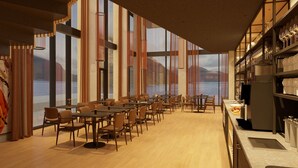 A spacious dining area with long tables and chairs, large windows with a view of mountains, and a kitchen area with shelves. - KG Hotel (Klaksvik)