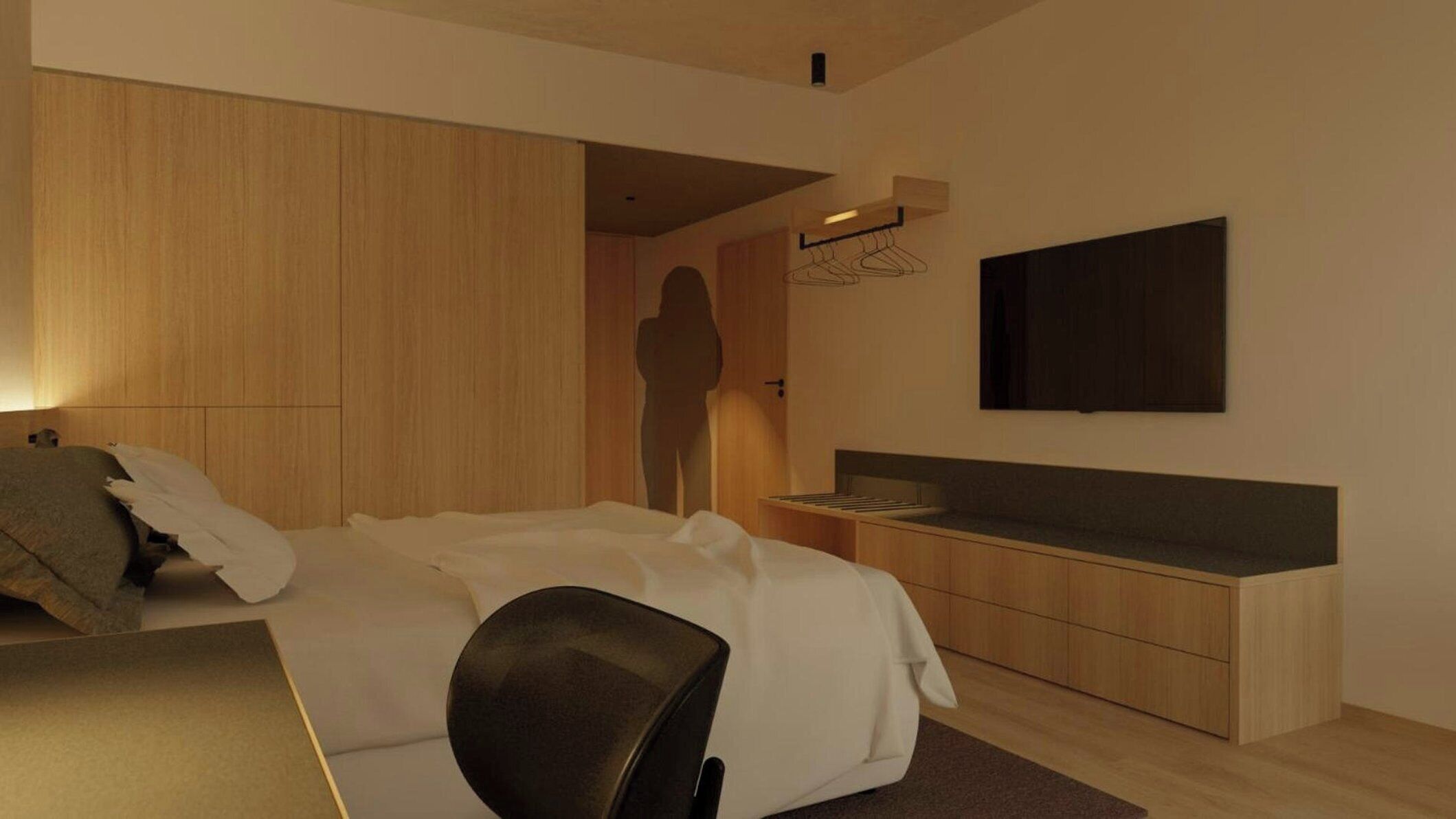 A modern hotel room with a bed, bedside table, and a flat-screen TV mounted on the wall.