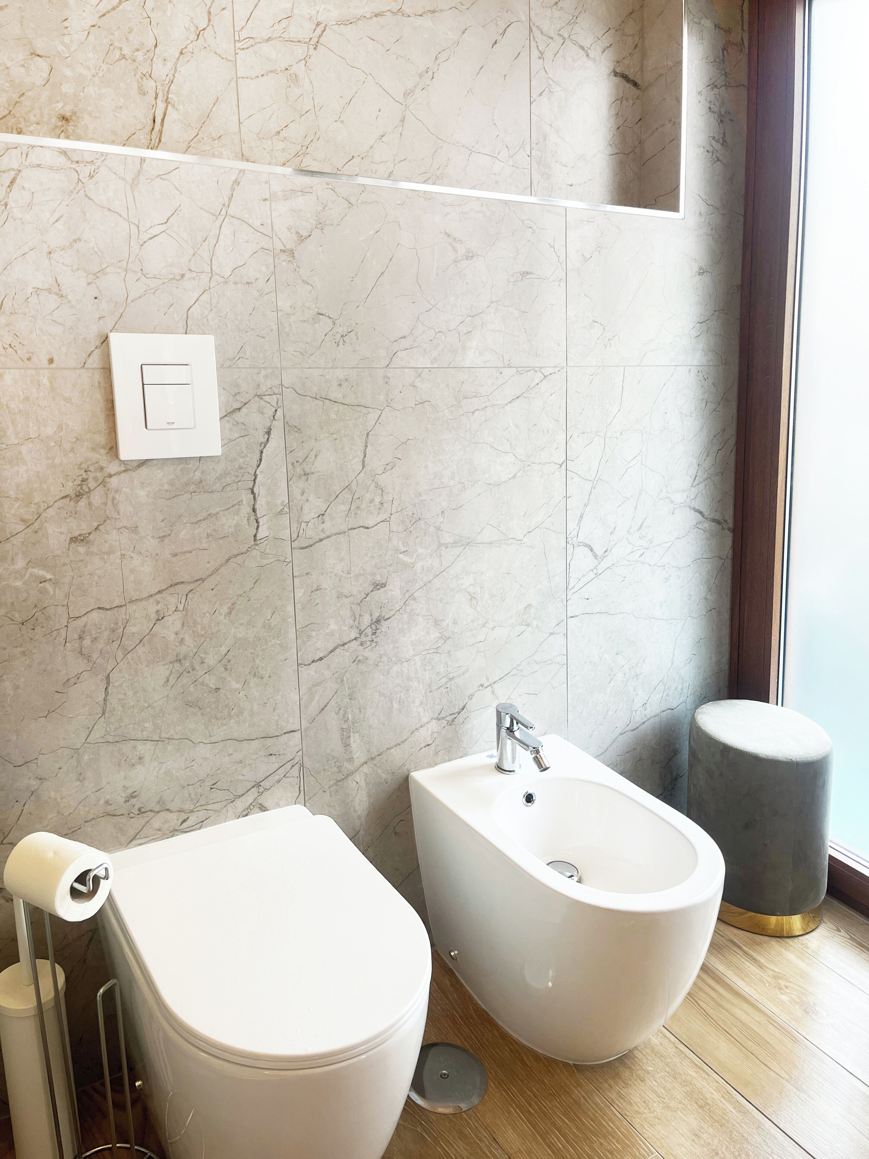 Une salle de bain avec des toilettes, un bidet et un mur en marbre.