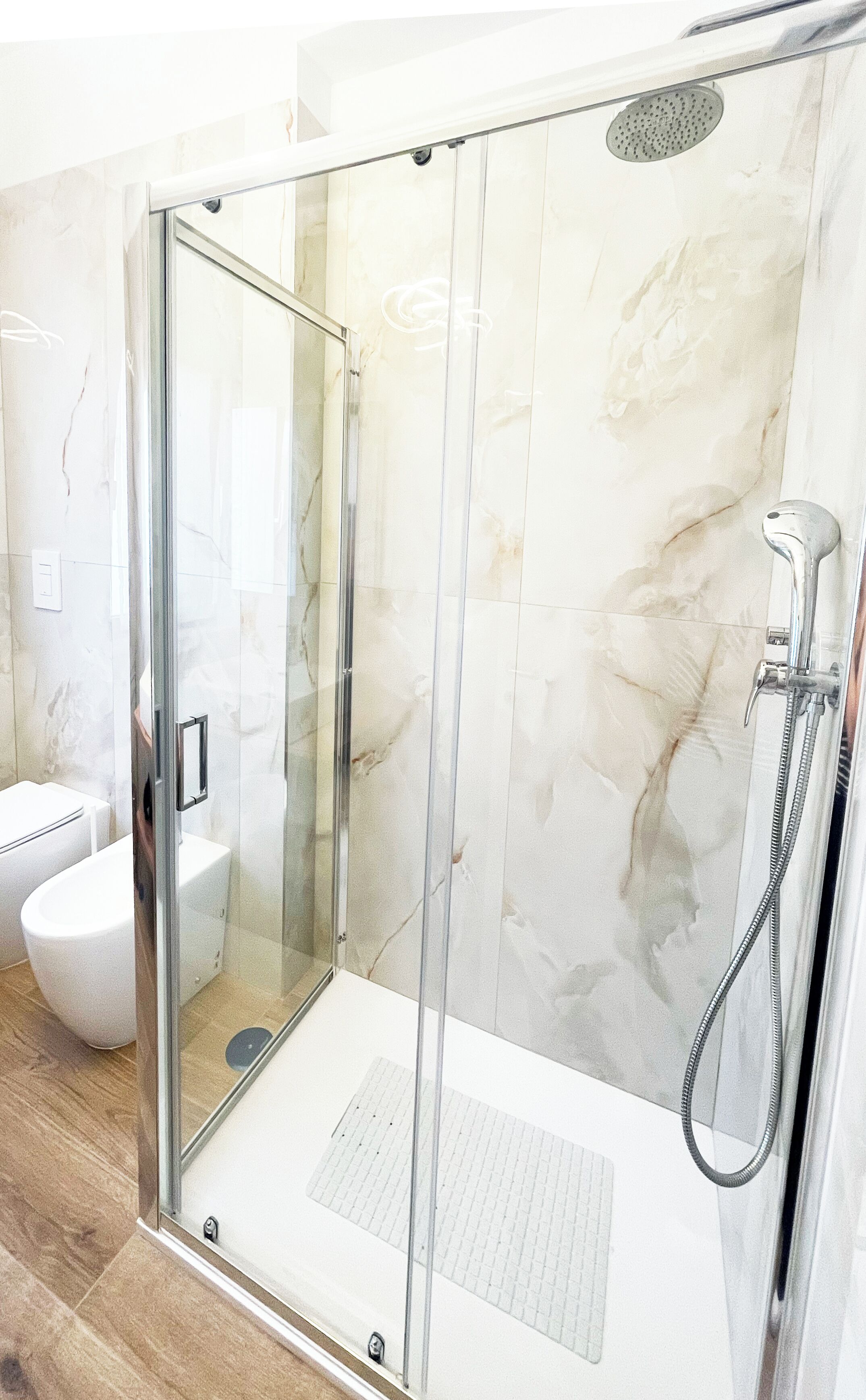 A modern bathroom with a glass-enclosed shower, a toilet, and a sink.