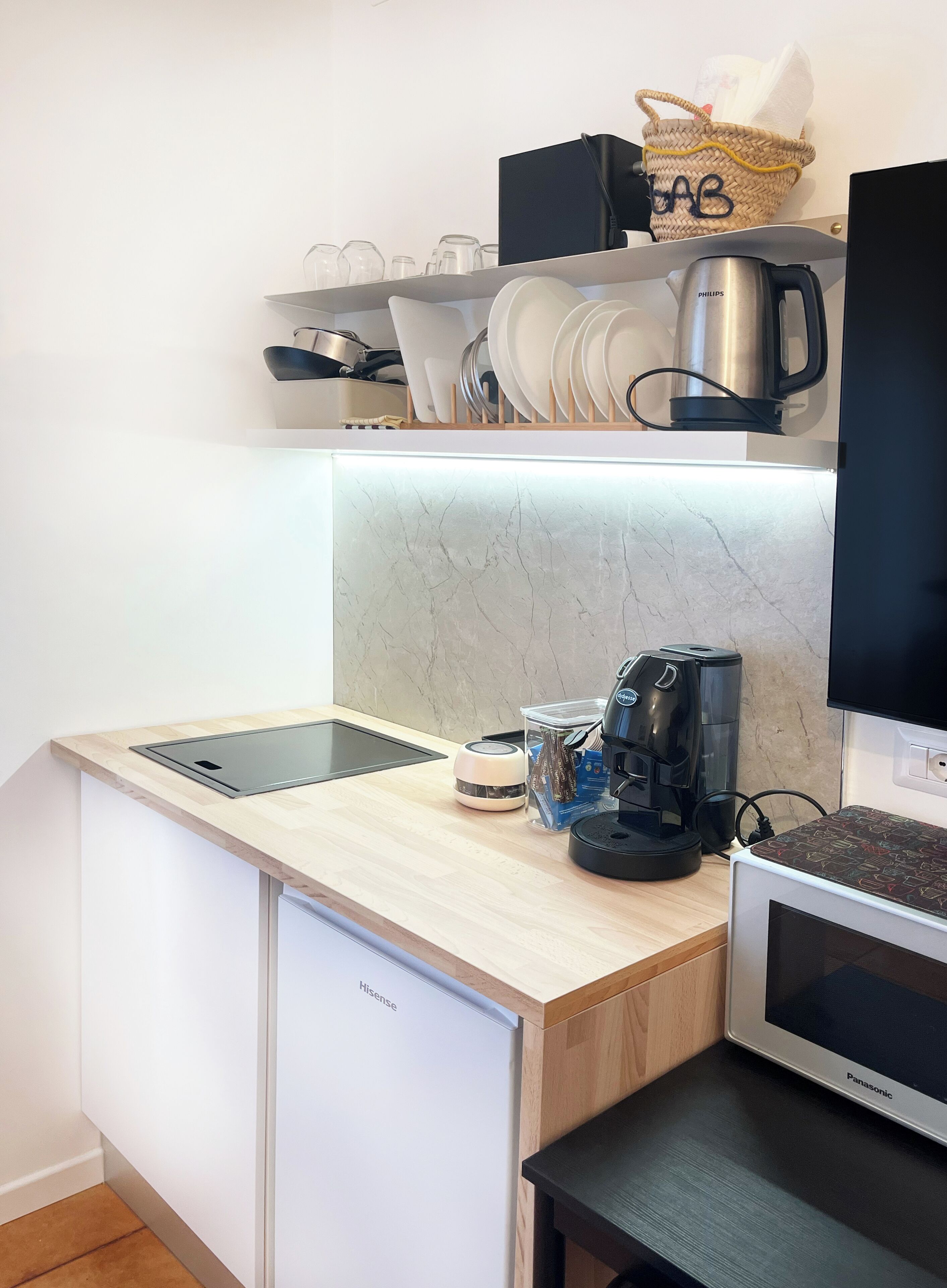 A compact kitchen with a built-in dishwasher, a coffee maker, and a microwave.