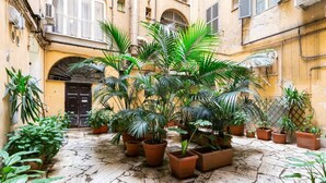 Une cour intérieure agrémentée de plantes en pot et dotée d’un sol en pierre.