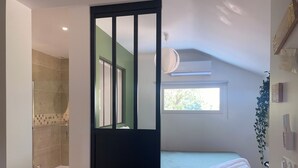 Une chambre à coucher avec un lit, une fenêtre et une salle de bain avec douche.