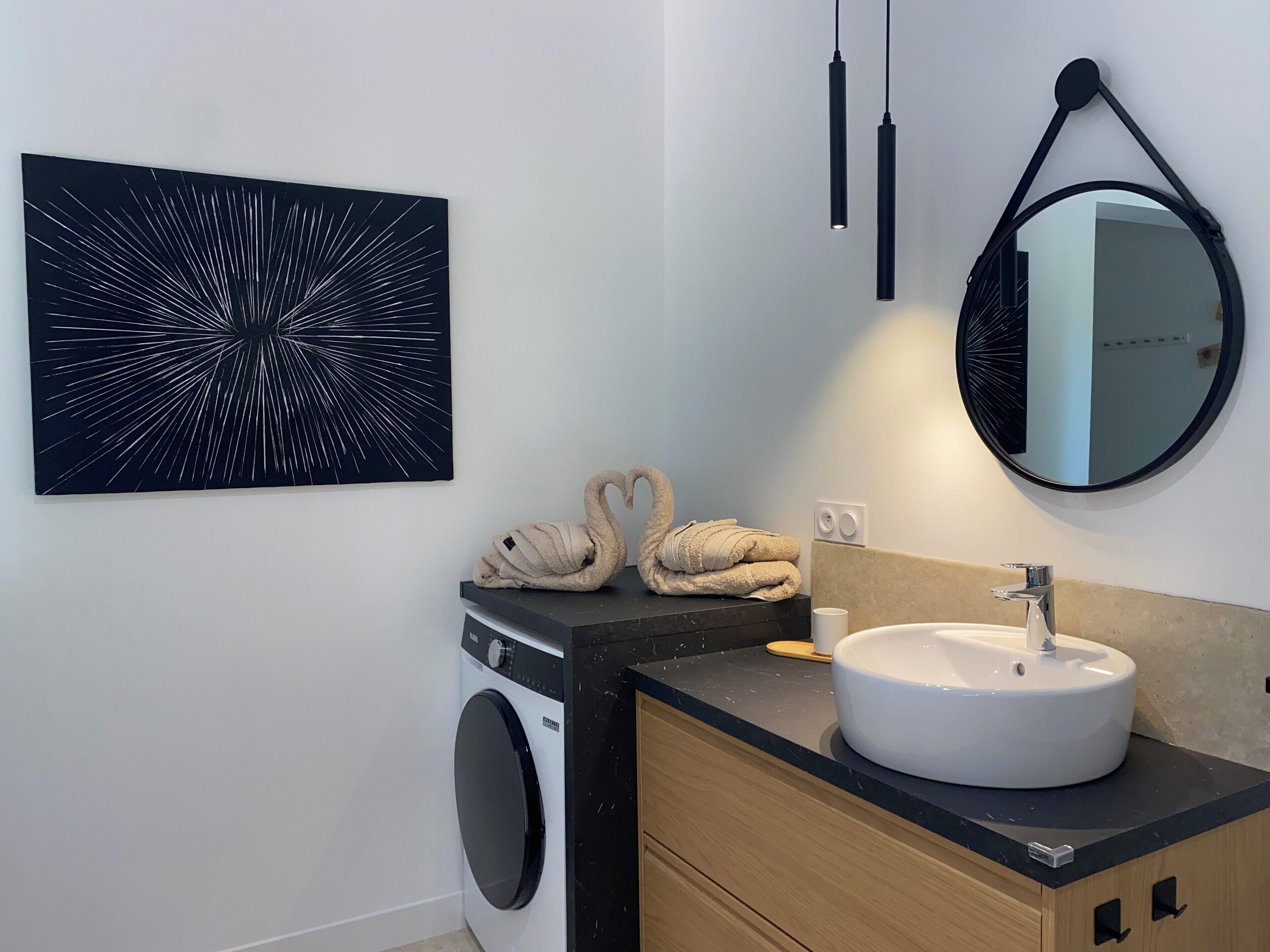 A modern bathroom with a washing machine, a sink, and a towel rack.
