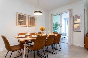 A dining area with a table set for six, surrounded by brown chairs, a hanging light fixture, and framed artwork on the walls. - Storey Lake 4BR Townhome - Pool & Themed Beds (Kissimmee)