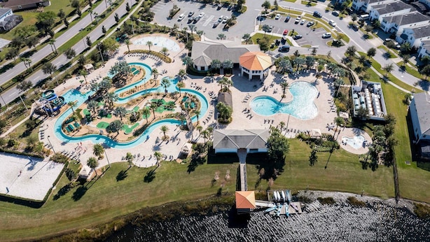 An aerial view of a resort with multiple swimming pools, a water park, and a central building with a red roof. - Storey Lake 4BR Home - Private Pool (Kissimmee)