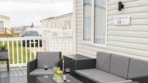 A covered outdoor area with wicker furniture, a white rug, and a sign reading "The Beach Hut C5". - The Beach Hut, Burghead Holiday Park (Burghead)