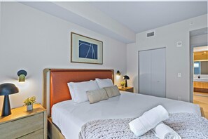 Ein Hotelzimmer mit einem Bett, Nachttischen, einem gerahmten Bild, einer Tür und einem Spiegel.