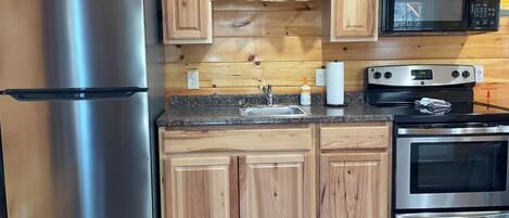 A kitchen with wooden cabinets, a stainless steel refrigerator, a microwave, and an oven.