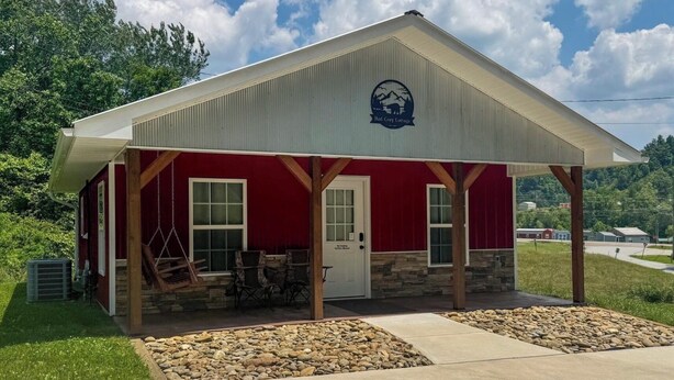 A Red Casey Cottage with a red exterior, a covered porch, and a stone foundation. - Red Cozy Cottage  1-bedroom cottage in charming Oneida, TN (Oneida)
