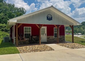 A Red Casey Cottage with a red exterior, a covered porch, and a stone foundation.