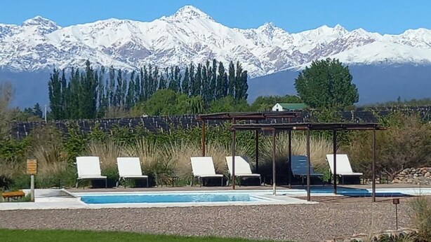 A pool area with lounge chairs and a gazebo, surrounded by a mountainous landscape. - Tupungato Divino (Tupungato)