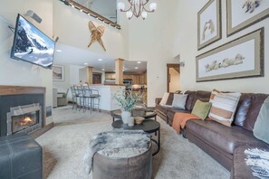 A spacious living room with a fireplace, a leather sofa, a coffee table, and a TV mounted on the wall. - Ski In&Ski Out Penthouse 3BD and Loft, Pool, HTub (Breckenridge)