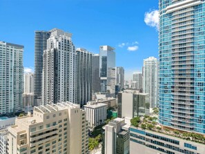 A high-rise urban area with modern buildings, including a prominent curved glass structure. - Brickell 1BR • Skyline / Pool • FIFA Fan Fest (Miami)