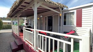 A covered outdoor area with a thatched roof, a white railing, and a bench. - 6 person mobile home "La Pagode" in a family campsite**** (Fréjus)