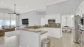 Eine moderne Küche mit weißen Schränken, Granit Arbeitsplatten, Edelstahlgeräten und einem Essbereich mit einer Chandelier.