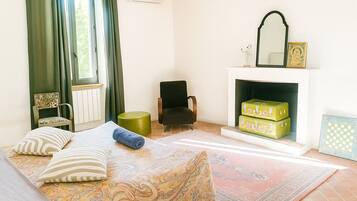 Une chambre à coucher avec un lit, une chaise, une cheminée et une fenêtre avec des rideaux.