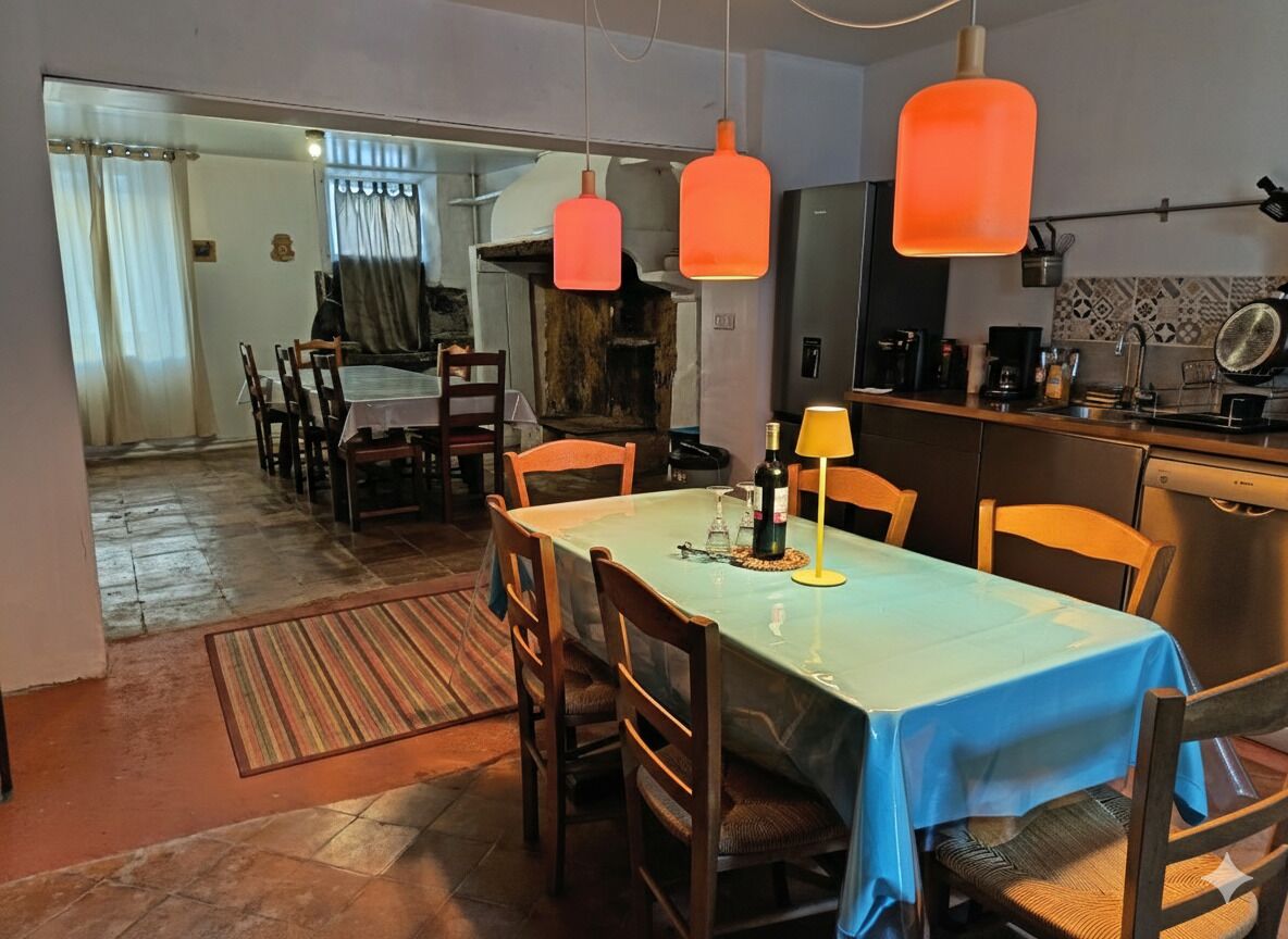 A dining area with a table set for four, a kitchen with modern appliances, and a rustic fireplace.