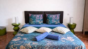A bed with floral-patterned bedding, two pillows, and a rolled towel.