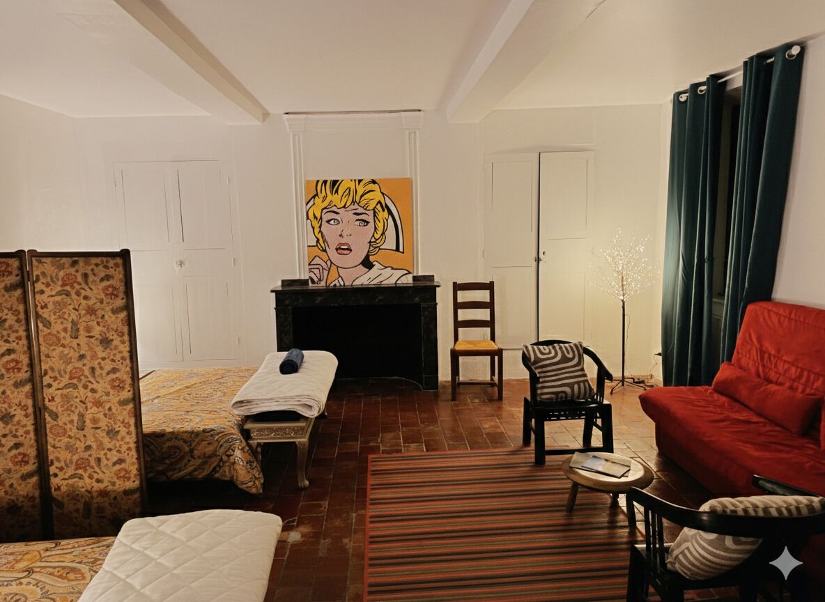 Een kamer met een bed, een stoel, een rode bank, een schilderij aan de muur en een open haard.
