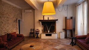 Ein gemütliches Wohnzimmer mit Steinwand, Kamin und einer großen gelben Pendelleuchte.