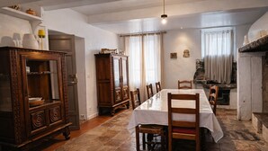 Ein Essbereich mit einem langen Tisch, Holzsesseln, einem Schrank und einem Kamin.