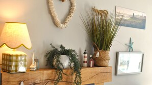 A fireplace mantel with a lamp, a potted plant, and a framed picture. - Mill View Cottage- charming coastal cottage (Saint Monans)