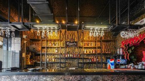 A bar area with a brick wall, shelves of liquor bottles, and a sign for 'Carlsberg Elephant'. - Super Deluxe Room Hotel Rockland (Kota)