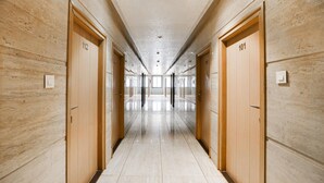 A long, well-lit hallway with wooden doors numbered 101 and 112, leading to rooms. - Super Deluxe Room Hotel Rockland (Kota)