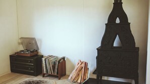 Een kamer met een houten vloer, een platenspeler, een stapel vinylplaten en een decoratieve stoel.