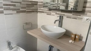 A bathroom with a white sink, a mirror, and a small cabinet. - The Attic (Bari)