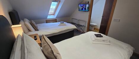 Una habitación de hotel con dos camas, un tragaluz, un televisor y un espejo.
