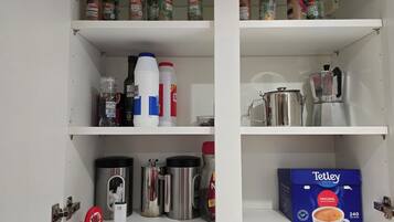 A kitchen pantry with shelves stocked with spices, condiments, and kitchenware.
