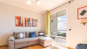 A modern living room with a grey sectional sofa, a white coffee table, and abstract wall art. - Sunrising Apartment by Atlantic Holiday (Santa Cruz)