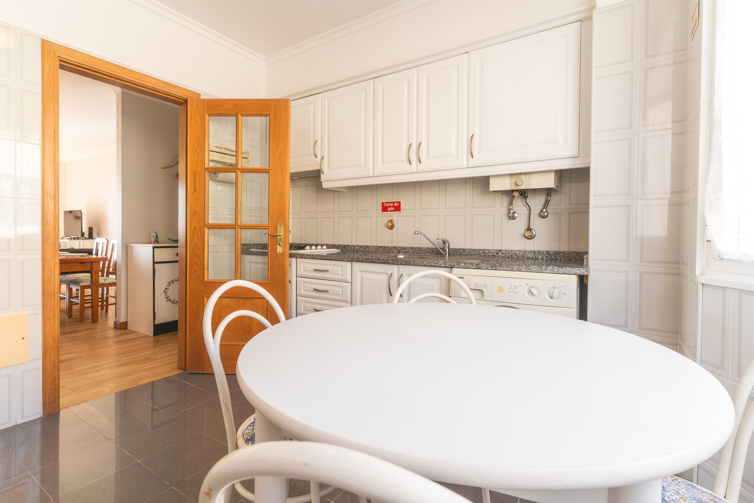 A kitchen with white cabinets, a granite countertop, and a white dining table with chairs.